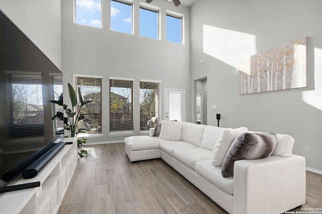 living room featuring a high ceiling, ceiling fan, and a healthy amount of sunlight