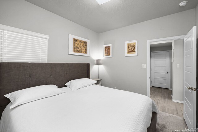 bedroom with light wood-type flooring and a textured ceiling