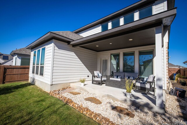 rear view of property with outdoor lounge area, a patio, and a lawn