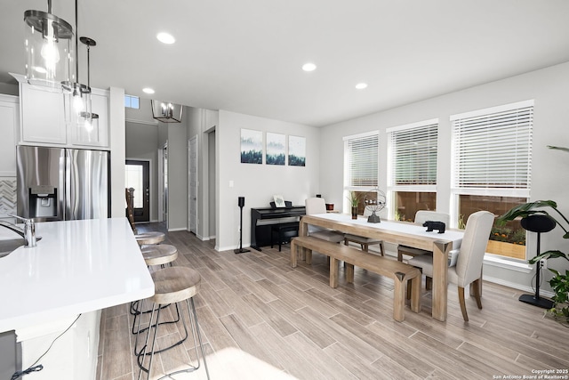 dining area featuring a notable chandelier, plenty of natural light, light hardwood / wood-style floors, and sink