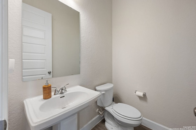 bathroom featuring wood-type flooring, toilet, and sink