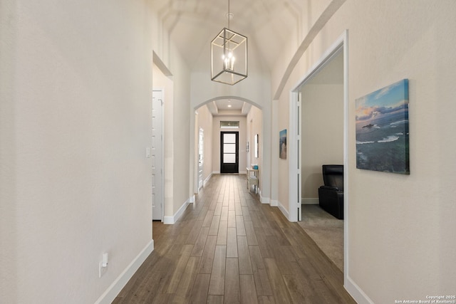 hall featuring dark hardwood / wood-style floors, a high ceiling, and an inviting chandelier