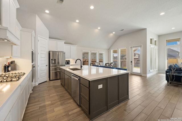 kitchen with decorative backsplash, appliances with stainless steel finishes, sink, a center island with sink, and white cabinetry