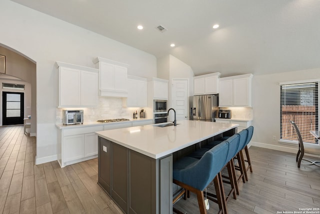 kitchen with a large island with sink, a breakfast bar, white cabinets, and stainless steel appliances