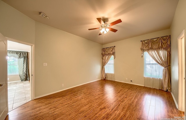 empty room with ceiling fan, plenty of natural light, and hardwood / wood-style flooring