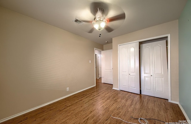 unfurnished bedroom featuring ceiling fan, a closet, and hardwood / wood-style flooring