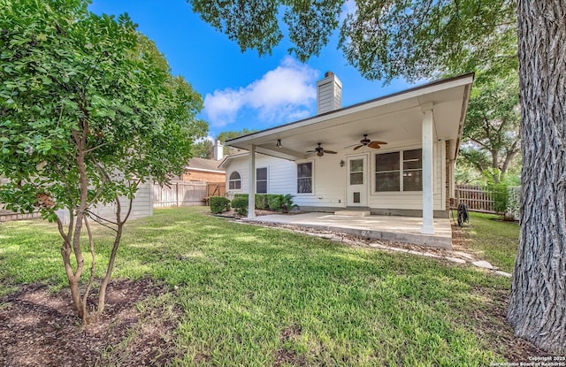 rear view of house with ceiling fan, a patio area, and a lawn