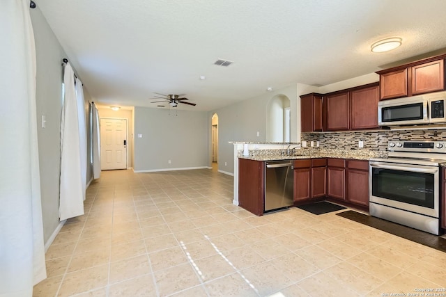 kitchen with kitchen peninsula, appliances with stainless steel finishes, tasteful backsplash, light stone counters, and ceiling fan