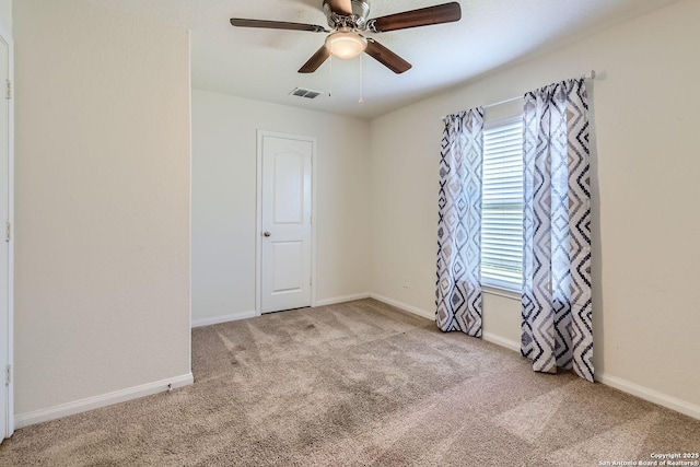 empty room with ceiling fan and light carpet