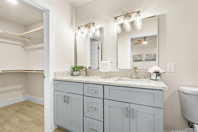 bathroom featuring ceiling fan, toilet, vanity, and hardwood / wood-style flooring