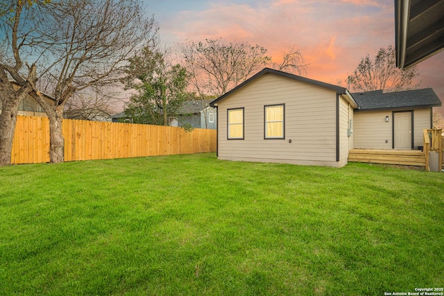 back house at dusk featuring a yard and a wooden deck