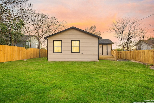 back house at dusk with a lawn