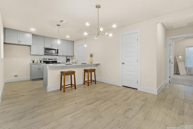 kitchen with pendant lighting, gray cabinets, stainless steel appliances, and tasteful backsplash