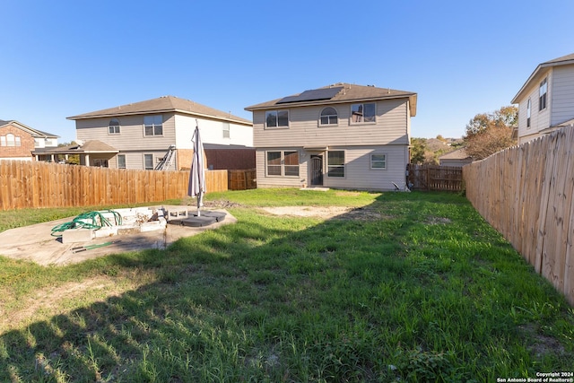 rear view of house featuring solar panels, a patio area, and a lawn