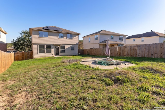 back of house with a yard, a patio, and solar panels