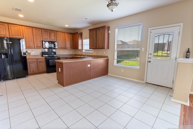 kitchen with black appliances, light tile patterned flooring, and sink