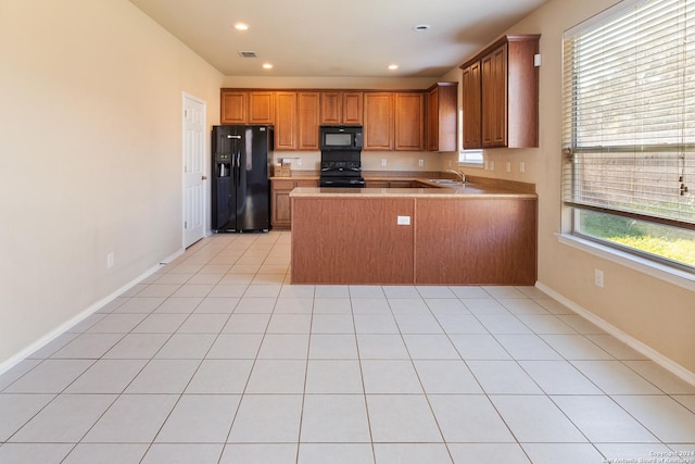 kitchen featuring sink, kitchen peninsula, plenty of natural light, light tile patterned floors, and black appliances