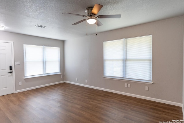 spare room with ceiling fan, plenty of natural light, dark wood-type flooring, and a textured ceiling