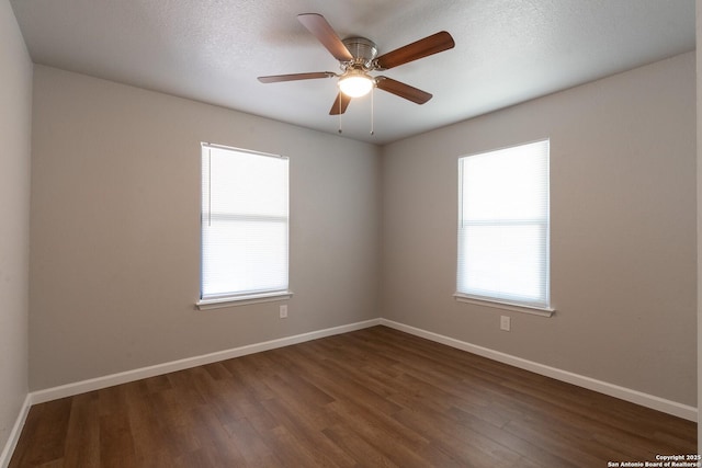 spare room featuring a textured ceiling, ceiling fan, a healthy amount of sunlight, and dark hardwood / wood-style floors