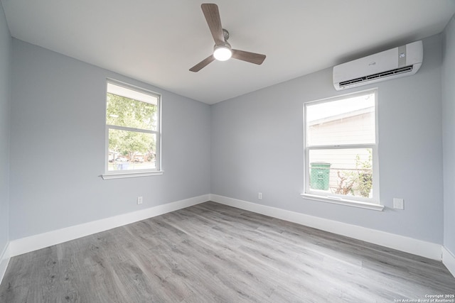 empty room featuring light hardwood / wood-style floors, a wall unit AC, and ceiling fan