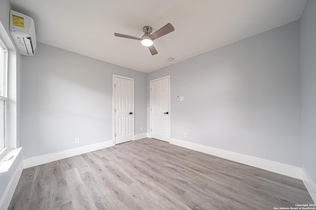 unfurnished room featuring ceiling fan, an AC wall unit, and light hardwood / wood-style flooring