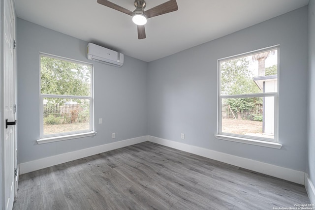 spare room with ceiling fan, a wall unit AC, and light hardwood / wood-style flooring