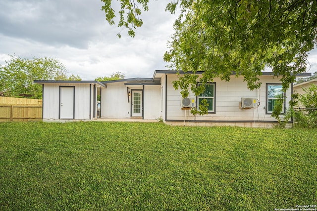 rear view of house with a yard, a wall mounted AC, and a storage shed