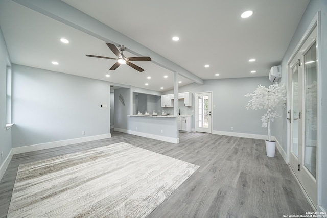 unfurnished living room with light wood-type flooring, lofted ceiling with beams, a wall unit AC, and ceiling fan