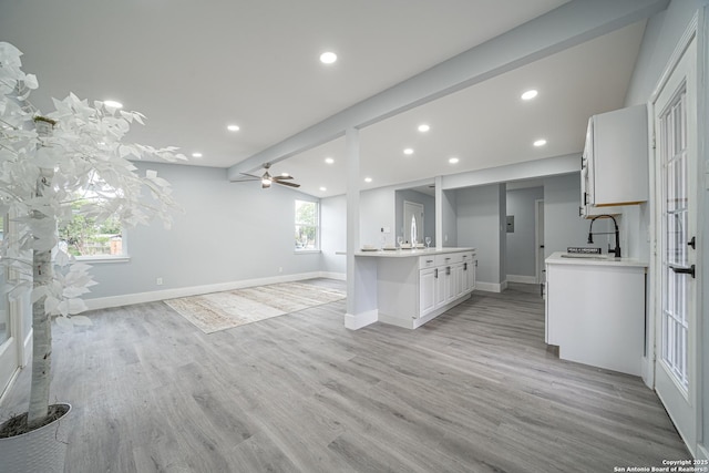 kitchen featuring light wood-type flooring, ceiling fan, a healthy amount of sunlight, lofted ceiling with beams, and white cabinetry