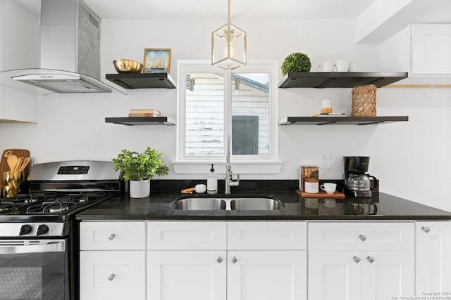 kitchen with sink, wall chimney exhaust hood, hanging light fixtures, white cabinets, and stainless steel range with gas stovetop