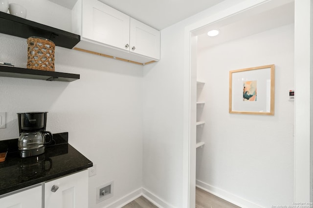 interior space with white cabinetry, dark stone counters, and light wood-type flooring