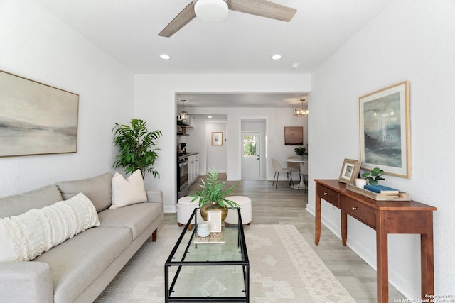 living room featuring light hardwood / wood-style floors and ceiling fan with notable chandelier