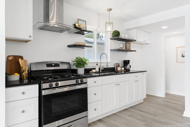 kitchen featuring stainless steel range with gas cooktop, sink, light wood-type flooring, island range hood, and white cabinetry