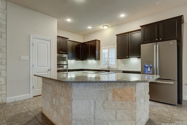 kitchen with a kitchen island, tasteful backsplash, appliances with stainless steel finishes, and dark stone counters