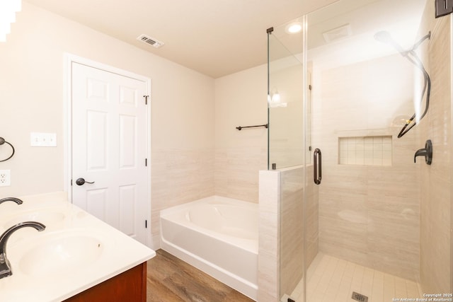 bathroom with hardwood / wood-style floors, vanity, and shower with separate bathtub