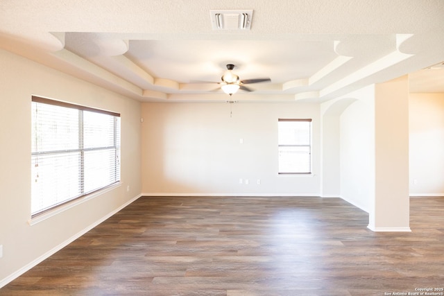 unfurnished room with ceiling fan, dark hardwood / wood-style flooring, a textured ceiling, and a tray ceiling