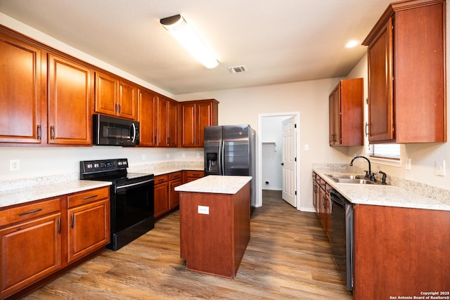 kitchen featuring black appliances, a kitchen island, sink, and hardwood / wood-style floors