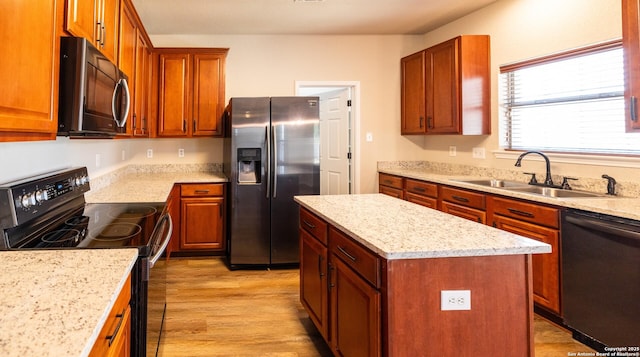 kitchen featuring light stone countertops, sink, a kitchen island, black appliances, and light wood-type flooring