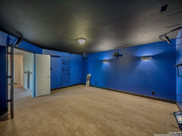 basement featuring light carpet and a textured ceiling