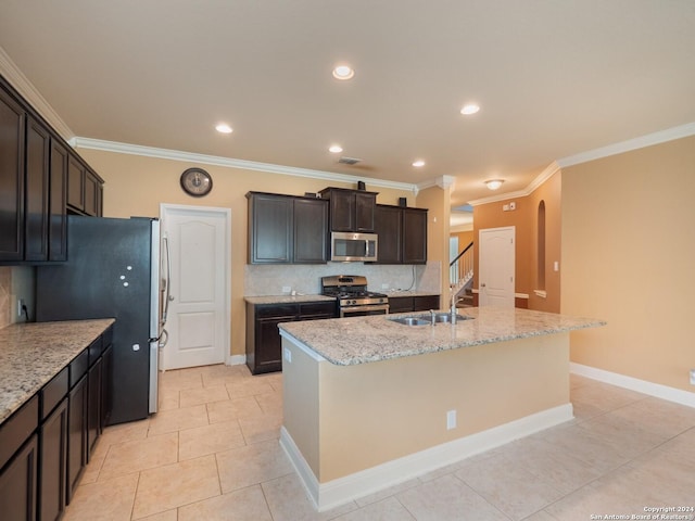 kitchen with light tile patterned flooring, light stone counters, stainless steel appliances, and an island with sink