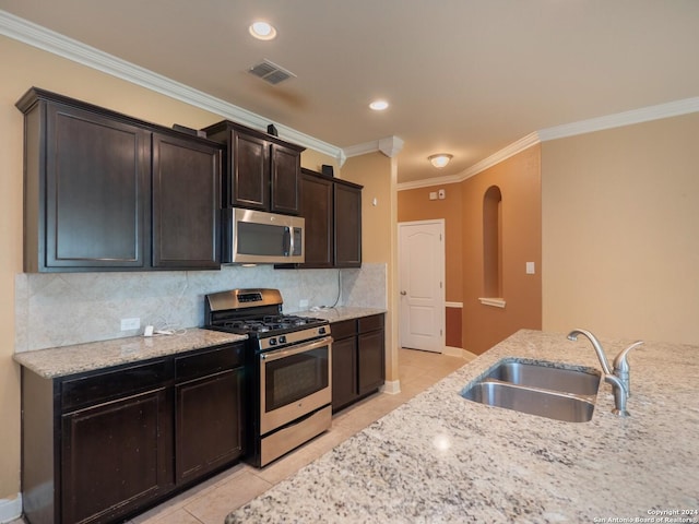 kitchen featuring light tile patterned floors, stainless steel appliances, light stone counters, and sink