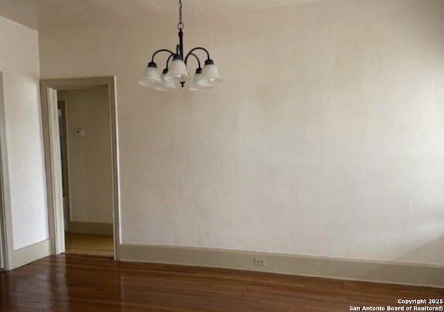 unfurnished dining area with dark hardwood / wood-style floors and an inviting chandelier