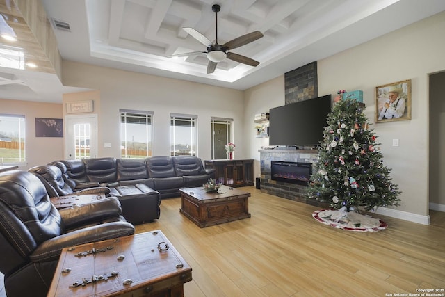 living room with coffered ceiling, ceiling fan, light hardwood / wood-style floors, beamed ceiling, and a large fireplace