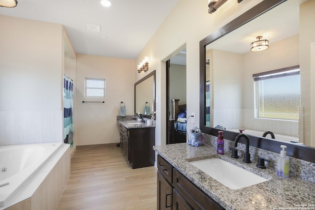 bathroom featuring plus walk in shower, vanity, a healthy amount of sunlight, and hardwood / wood-style flooring