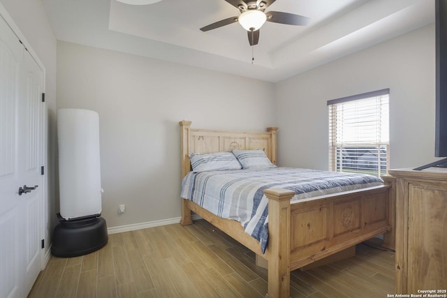 bedroom with ceiling fan, a closet, and a tray ceiling