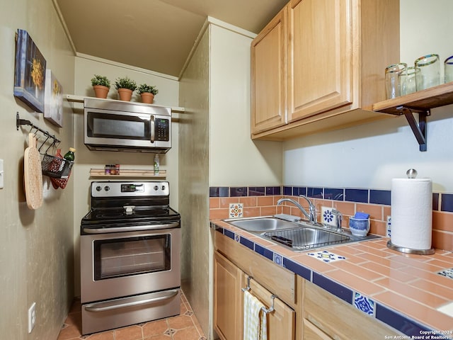 kitchen with light brown cabinetry, stainless steel appliances, sink, tile countertops, and light tile patterned flooring