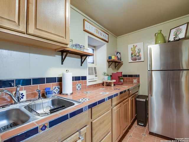 kitchen with tile counters, sink, tasteful backsplash, stainless steel fridge, and light tile patterned flooring