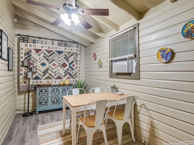 dining room with hardwood / wood-style floors, lofted ceiling with beams, ceiling fan, and wood walls