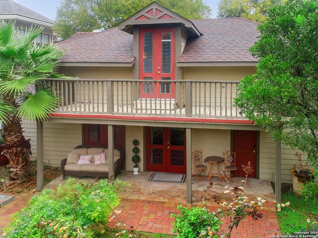 back of property with a balcony, a patio, and french doors