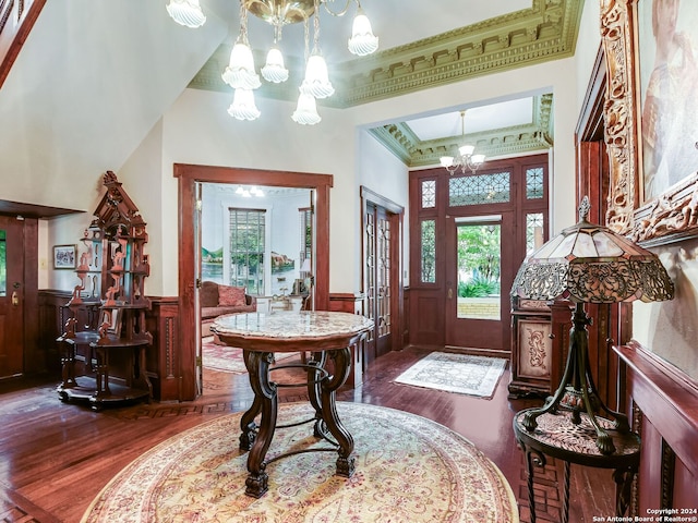 foyer entrance with crown molding, french doors, dark wood-type flooring, and an inviting chandelier